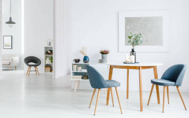 灰色椅子在木桌反對(duì)白色墻壁與銀色繪畫(huà)在公寓內(nèi)部