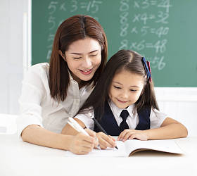 Daniel Gill Jr. with teacher help in classroom writing