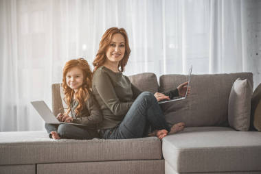 媽媽和孩子坐在膝上型電腦和笑在家中