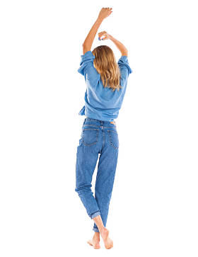 反观牛仔裤时尚。在白色背景下站在蓝色牛仔裤上的年轻金发女郎的全长肖像