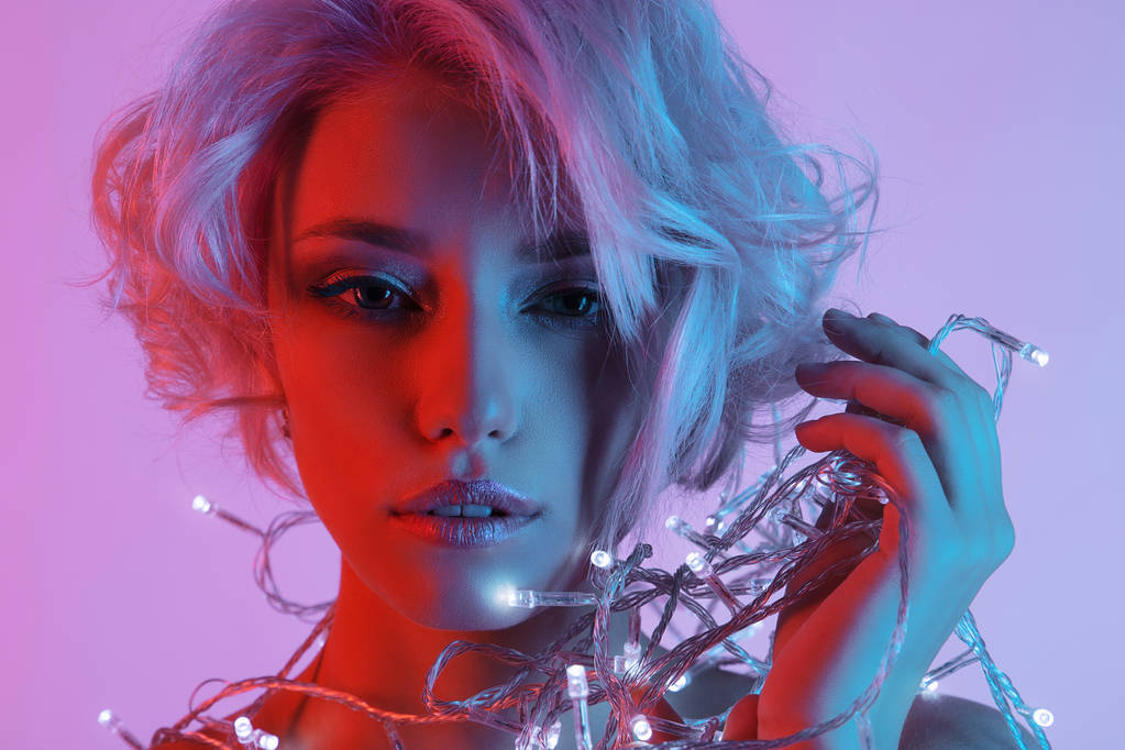 美丽的金发女人在彩色光. 短的金发. 有节日花环的性感女孩。新年快乐
