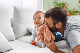 父亲在家里玩他微笑着的小儿子