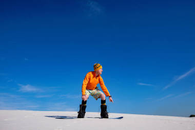 阳光明媚的日子, 沙漠中的沙子登入。滑稽的人准备跳跃, 而滑雪在沙丘上, 对蓝天。广角