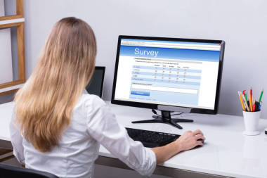 在計(jì)算機(jī)上填寫(xiě)在線調(diào)查表的女實(shí)業(yè)家的后視圖