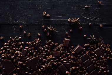 木桌上的八角、巧克力片和咖啡豆堆的高視圖