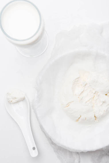 白色表面勺子棉布玻璃上的干酪的頂部視圖