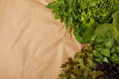 新鮮各種葉菜在皺巴巴的紙上的頂部視圖