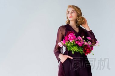低角度的優(yōu)雅年輕女子與美麗的花朵看著遠離灰色孤立