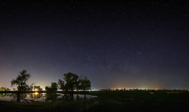 夜空中有銀河系的星星的空間。與河和樹的風(fēng)景被拍照在長的曝光
