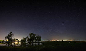 夜空中有银河系的星星的空间。与河和树的风景被拍照在长的曝光