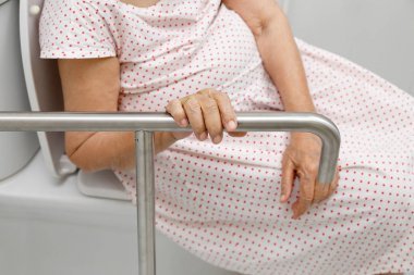 老妇人手持扶手在洗手间.图片