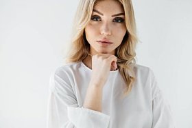 在白色的背景下, 白色服装的美丽的金发女郎肖像