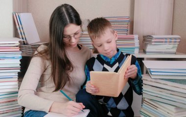 媽媽和兒子一起讀了一本書。戴眼鏡的媽媽在筆記本里寫東西