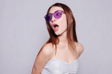 在眼鏡白色背景的美麗的女孩的肖像。閉上年輕開(kāi)朗美麗的女孩的肖像與深色長(zhǎng)發(fā)微笑著牙齒, 看著相機(jī)女孩驚訝