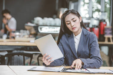 年輕有魅力的女人打電話給她的銀行服務(wù)咨詢最后的交易, 同時正在使用在線銀行在筆記本電腦上。有智能手機會話的女性商務(wù)人士
