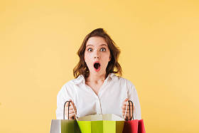 年轻的惊讶的女士站在手和惊异看着相机上的粉红色背景照片