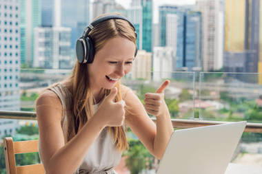 年輕女子在一個(gè)大城市的背景下, 在陽臺(tái)上教一門外語或在互聯(lián)網(wǎng)上學(xué)習(xí)一門外語。網(wǎng)上語言學(xué)校生活方式