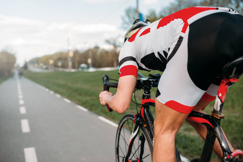 男骑自行车的头盔和运动服骑脚踏车, 后视图  男骑自行车的头盔和运动服骑脚踏车, 后视图