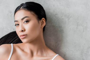 美麗的黑發(fā)亞洲女孩看著相機, 灰色