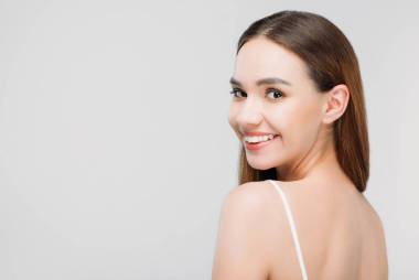 美麗的微笑的女孩看著相機, 孤立的灰色