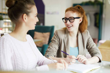 兩個(gè)年輕的女商人坐在舒適的咖啡館和談話在會(huì)議上