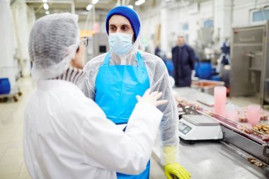 兩名魚廠工人保護(hù)工作服探討海鮮加工方法