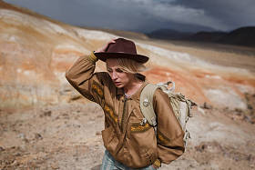 肖像美丽的年轻女孩在野兔, 帽子和背包旅行之间的野生沙子