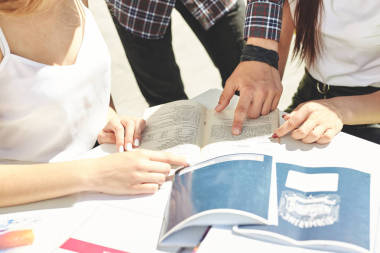 男生向女生解释一些事情，并在笔记本上显示出来。三个快乐的高中生的肖像。同学们一起学习，一起做作业，花时间玩乐