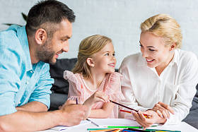 快乐的父母和可爱的小女儿在家里画画用彩色铅笔