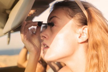 年轻妇女调整他们的化妆在汽车上度假