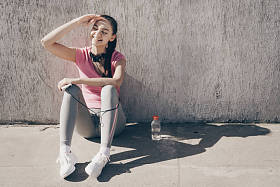 微笑的年轻女子坐在地上, 休息后, 一个艰苦的锻炼室外