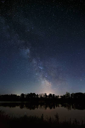 夜空中有星星的空间。与河和树的风景被拍照在长的曝光