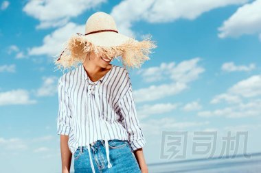 微笑非洲美國(guó)婦女在草帽反對(duì)藍(lán)色多云天空