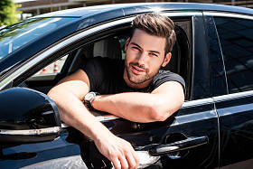 微笑英俊的年轻人坐在他的车肖像