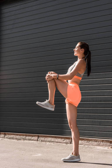 美麗的運(yùn)動(dòng)?jì)D女伸展腿在城