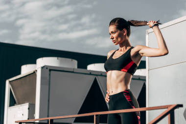 在屋顶运动服的年轻运动员与马尾辫