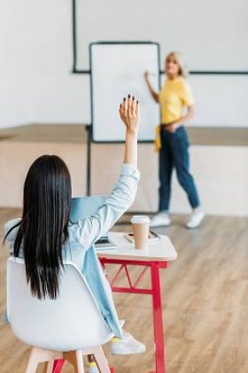 学生举手回答教师问题的后视图