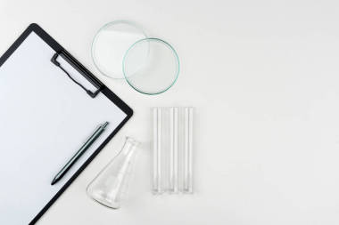 實驗室設備的高級視圖。桌子上有鋼筆、燒瓶、試管和手表玻璃的剪貼板