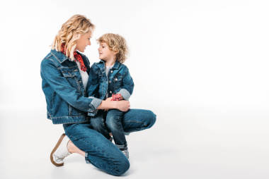 快樂(lè)的母親和兒子蹲著, 看著彼此孤立的白色