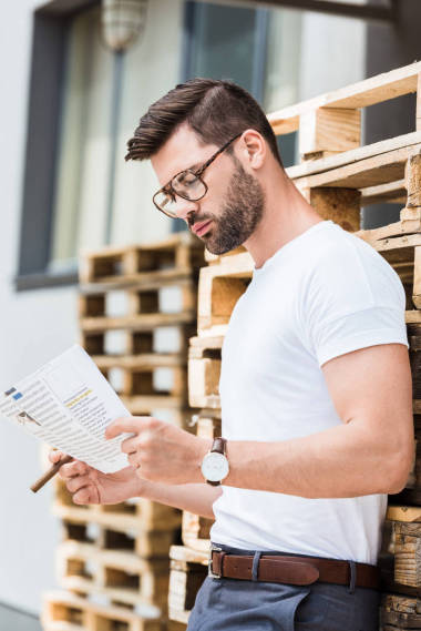 英俊的胡子商人與雪茄和文件在手站在木制調(diào)色板