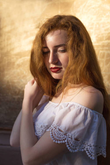 特寫肖像的神話般的 redhaired 婦女與紅唇擺在墻上的太陽光線