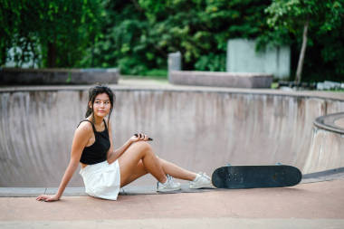 亞洲中國女孩在 skatepark 的手機和溜冰肖像