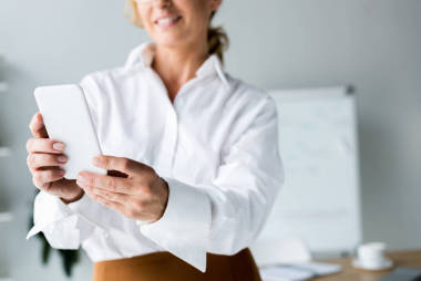 被裁剪的形象微笑的商人采取自拍智能手機(jī)在辦公室