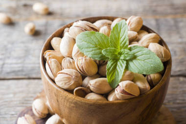 美味的盐渍开心果和新鲜薄荷叶的木质背景