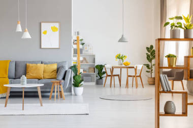 真实照片的露天空间内部与黄色垫子和毯子上的灰色沙发在生活区和木桌椅在用餐区