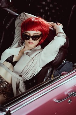 時(shí)尚女孩的高角度觀在風(fēng)衣和太陽鏡坐在復(fù)古車