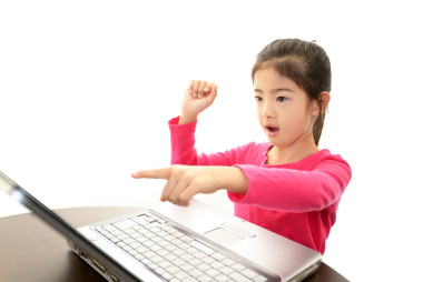 微笑女孩使用的便携式计算机图片