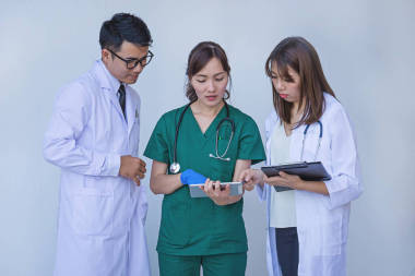 醫(yī)生和護(hù)士檢查片劑設(shè)備上的病人信息