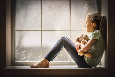 女孩看窗外拿著泰迪熊