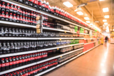 模糊的軟飲料通道在美國(guó)商店。負(fù)擔(dān)得起, 品種繁多的含糖飲料, 加劇了美國(guó)的肥胖問(wèn)題在貨架上陳列的模糊飲料瓶, 顧客購(gòu)物